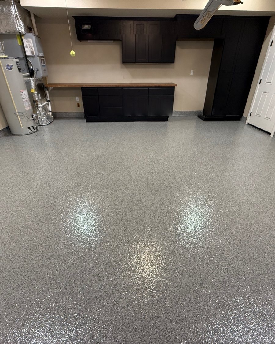 Finished residential garage floor with a gray flake coating and black cabinets