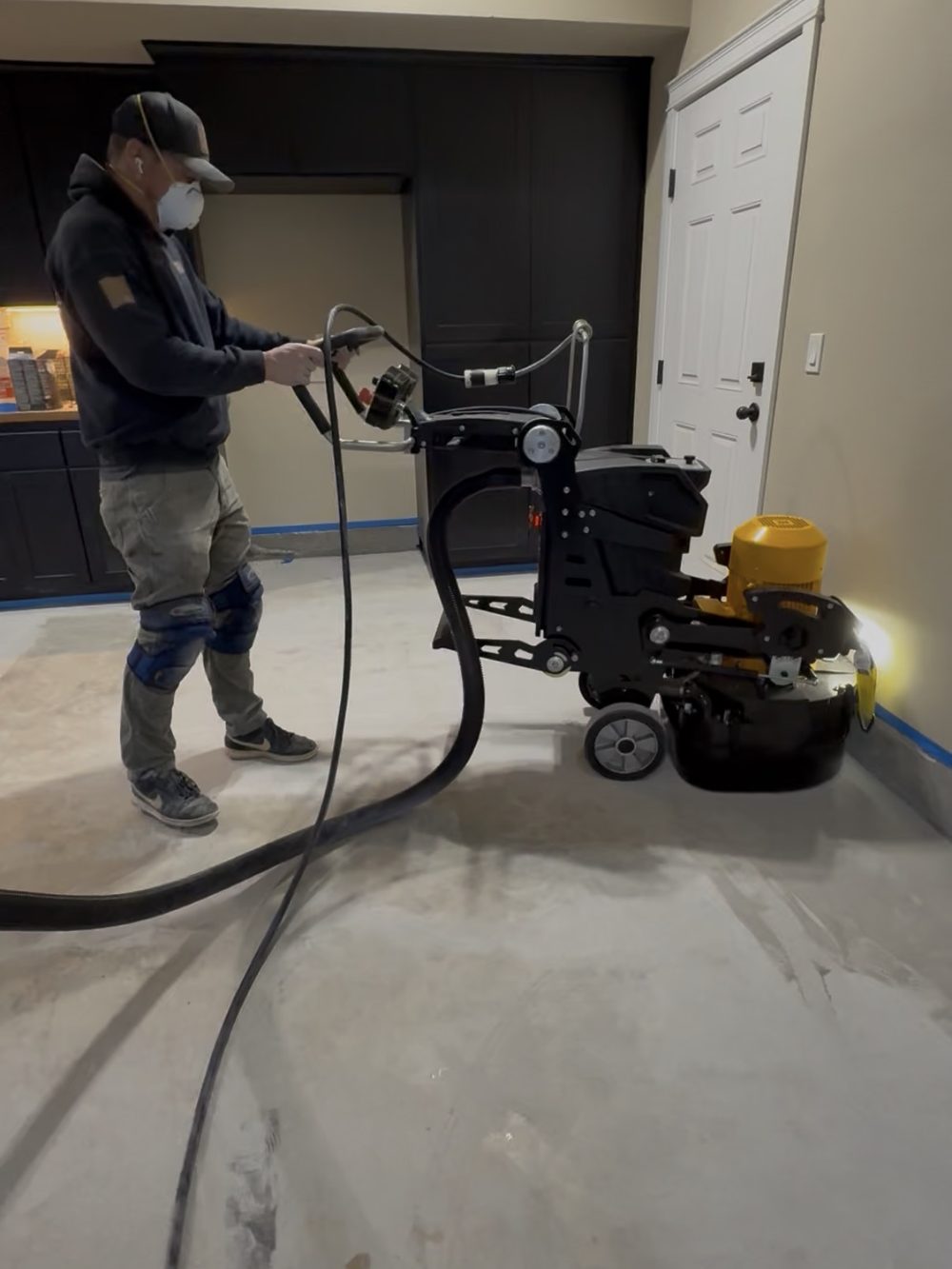 Technician diamond-grinding a concrete floor to prep it for coating